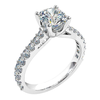 A platinum or white gold cushion cut diamond solitaire engagement ring with diamonds on the band in a shared claw setting