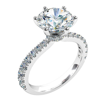 A platinum or white gold round brilliant cut six claw solitaire engagement ring with diamonds on the band and a hidden halo