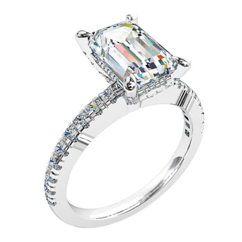 A platinum or white gold emerald cut diamond solitaire engagement ring with diamonds on the band. Complimented with a diamond hidden halo surrounding the centre stone.
