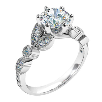 A platinum or white gold round cut diamond solitaire engagement ring with diamonds in a petal design on the band. Designed with a milgrain bezeled finish.