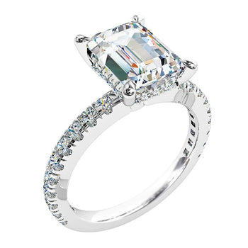 A platinum or white gold emerald cut diamond engagement ring with diamonds on the band and a hidden halo