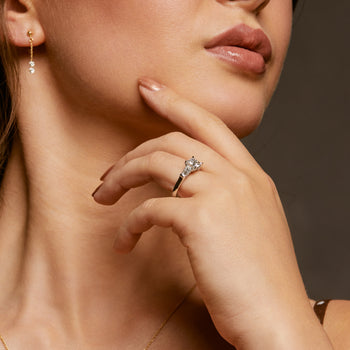 A woman wearing an asscher cut diamond solitaire trilogy engagement ring