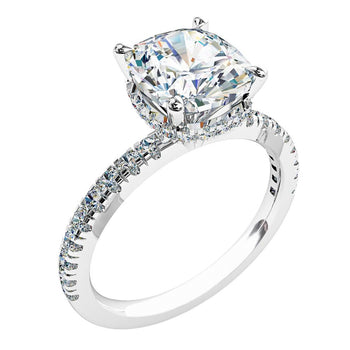 A platinum or white gold cushion cut diamond solitaire engagement ring with diamonds on the band and a hidden halo