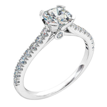 A white gold cushion cut diamond solitaire engagement ring with side diamonds and a diamond under the coronet