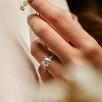 A woman wearing an cushion cut diamond solitaire with diamonds on the band engagement ring