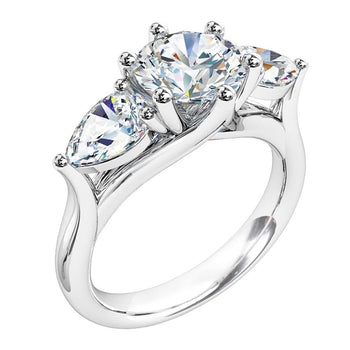 A platinum or white gold round brilliant cut diamond solitaire trilogy engagement ring with pear cut diamond sides