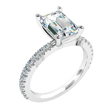 A platinum or white gold emerald cut diamond solitaire engagement ring with diamonds on the band in a claw setting