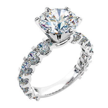 A platinum or white gold round brilliant cut diamond solitaire engagement ring with diamonds on the band in a shared claw setting