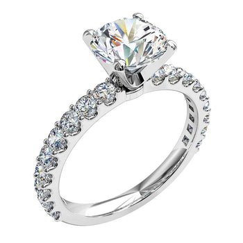A platinum or white gold round brilliant cut diamond solitaire four claw engagement ring with diamonds on the band in a shared claw setting