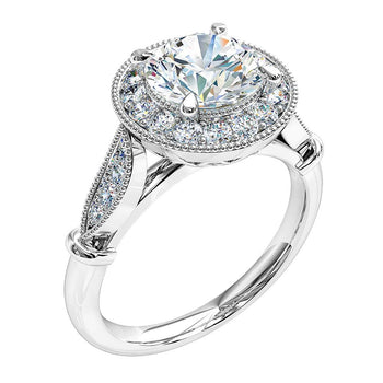 A platinum or white gold round brilliant cut diamond cluster halo engagement ring complimented by a grain set diamond band and milgrain finish