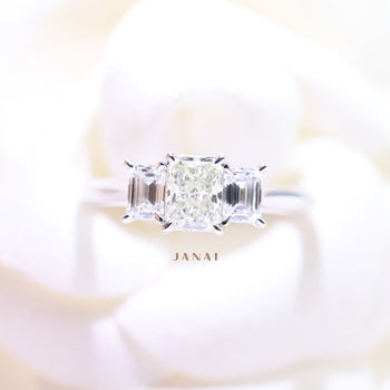 A white gold radiant cut diamond solitaire trilogy engagement ring with two matching emerald cut diamonds