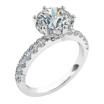 A platinum or white gold round brilliant cut diamond solitaire engagement ring with diamonds on the band and a hidden halo