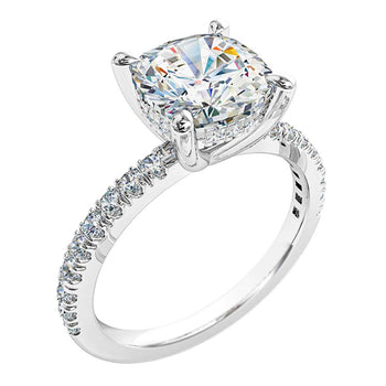 A platinum or white gold cushion cut diamond solitaire engagement ring featuring an individual claw set diamond band and a hidden halo